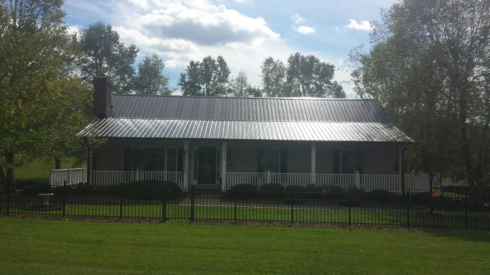 Gray metal roof on a brick ranch with a full width front porch — Gutter Guard Installation work by our crew in Holland